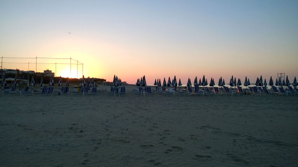 Closed umbrellas on the beach at sunset